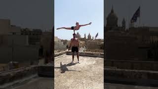 Girl Balances On Top Of Guy's Head In Single Handstand Position while Practicing On Roof - 1217961